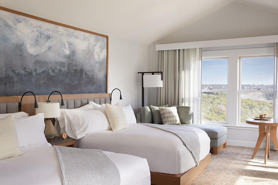 spa like guest room with blue and white abstract art behind the two full size beds - outside of the window is a sweeping view of the texas low country