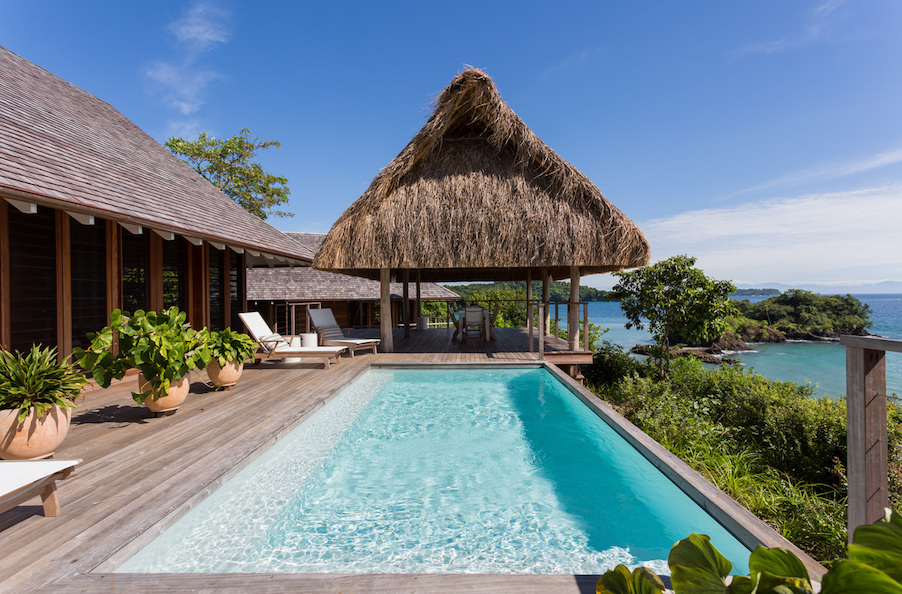 island retreat with a private swimming pool and ocean views. thatched roofs line the top of the image