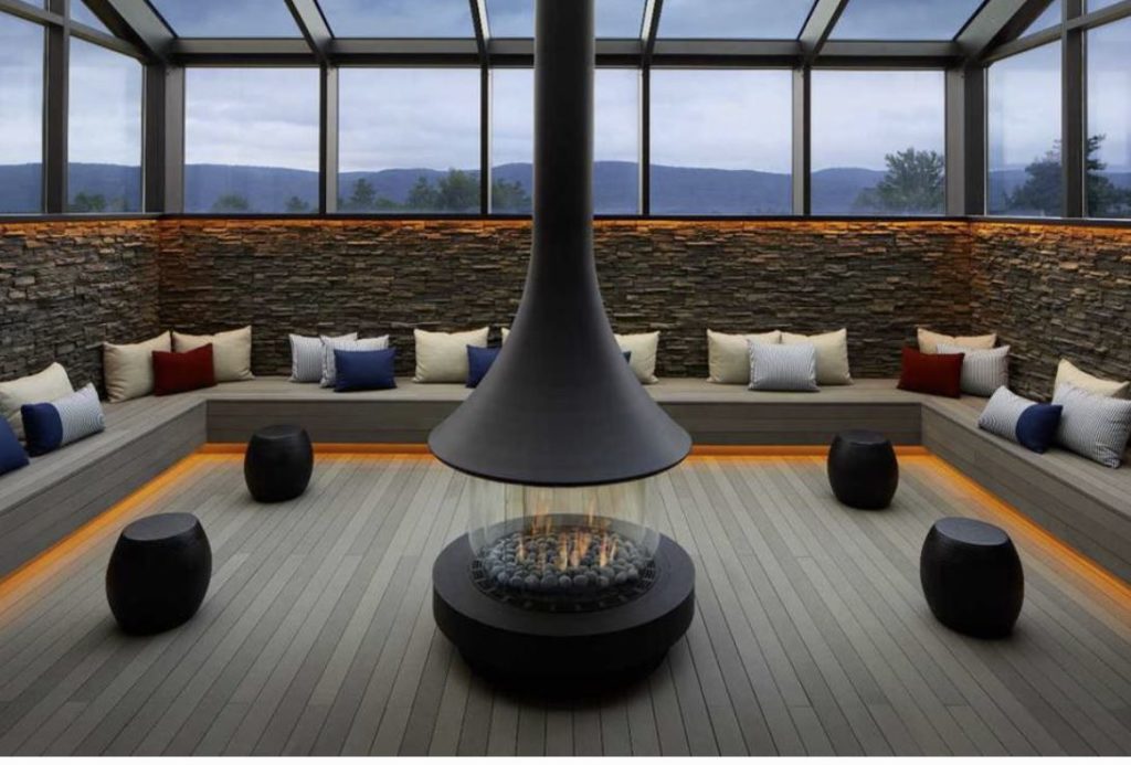 indoor firepit with bench seating surrounding and looking out to views of the bekshires