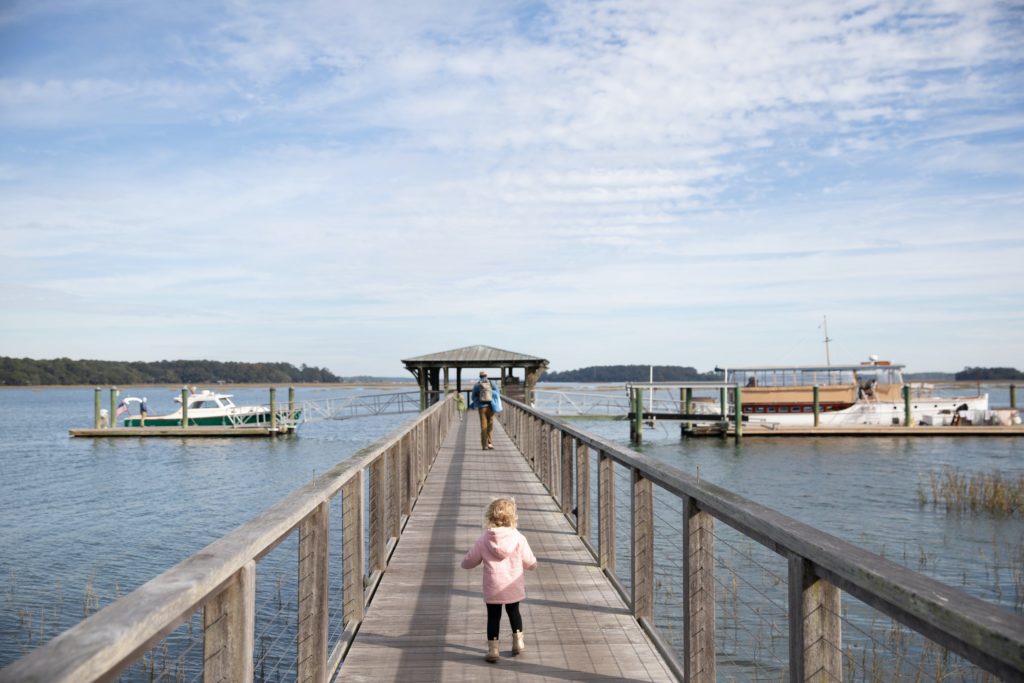 toddler running down a dock on lake water