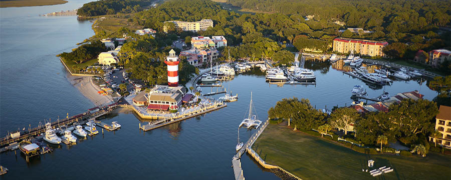aerial view of a marina cove with a large lighthouse painted in red and white stripes.