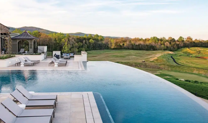infinity edge pool looking over a golf course with some small italianate structures in the background of the pool