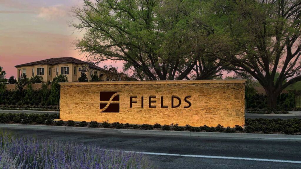 rendering of a community sign saying Fields - with a home in the background