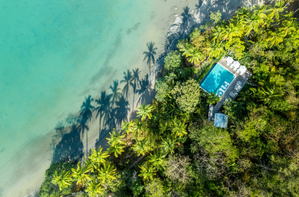 aerial photo of a secluded pool on an island - nextled amongst thick forest greenery